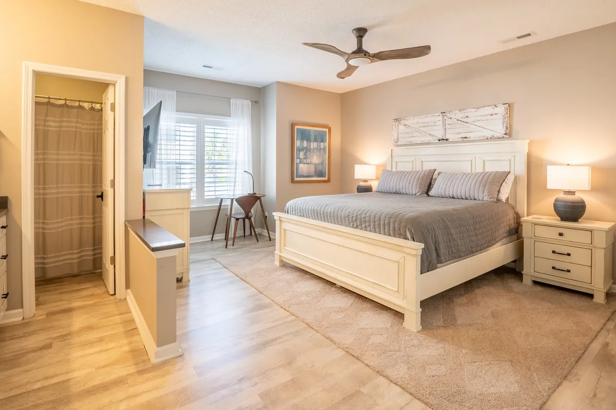 A serene bedroom with a comfortable bed, inviting window seating area for reading or morning coffee, stylish artwork, and nightstands. The large window suggests potential for natural light and stargazing, reinforcing the private, restful retreat described.