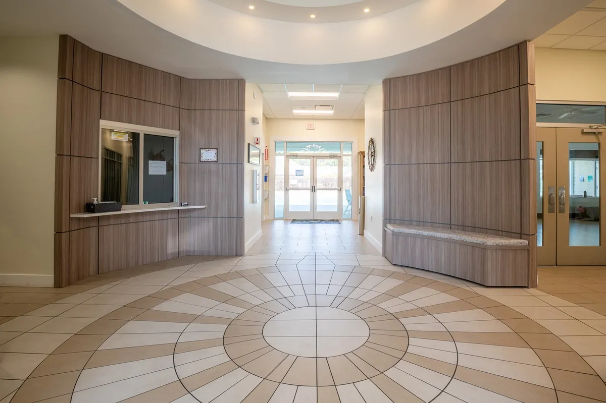 A spacious reception area with circular tile patterns, large windows, a waiting bench, and an inviting, calm mood.